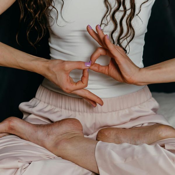 Woman in a calm seated meditation pose, hands in a mudra.